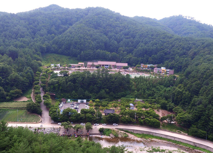 초록빛 산속에 둘러쌓여있는 캠핑장 전경